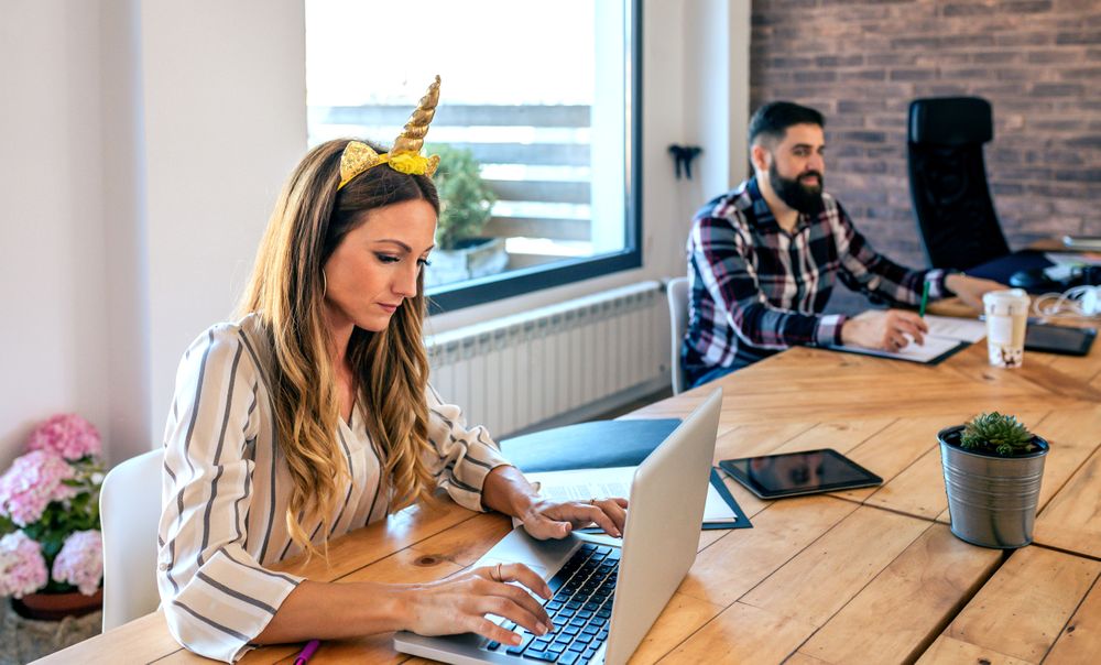 Businesswoman with unicorn headband working while her partner looks at her