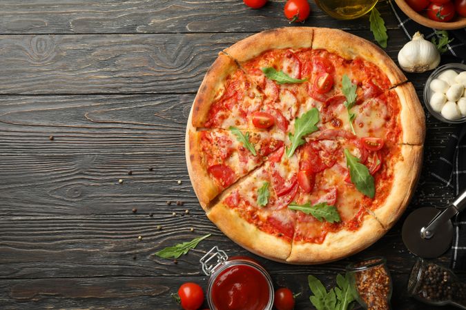 Tasty pizza and ingredients on wooden background
