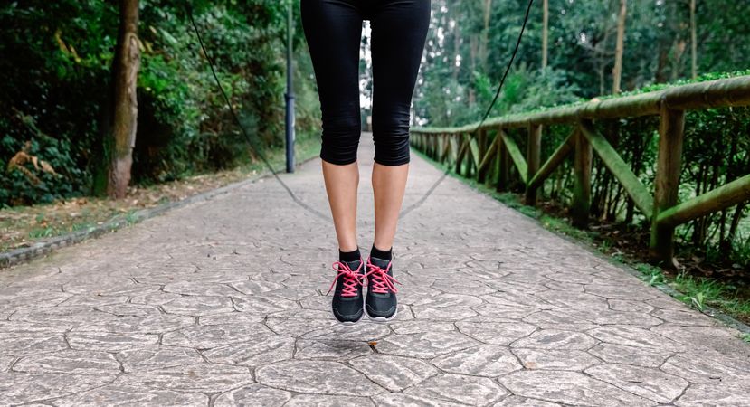 Feet of unrecognizable woman jumping with skipping rope