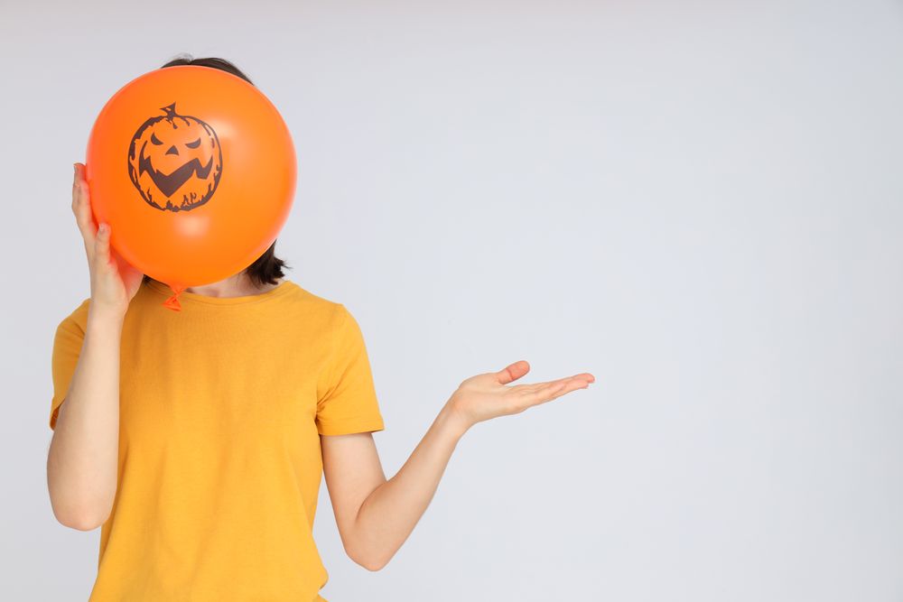 Concept of Halloween, Woman holds Halloween balloon on light background