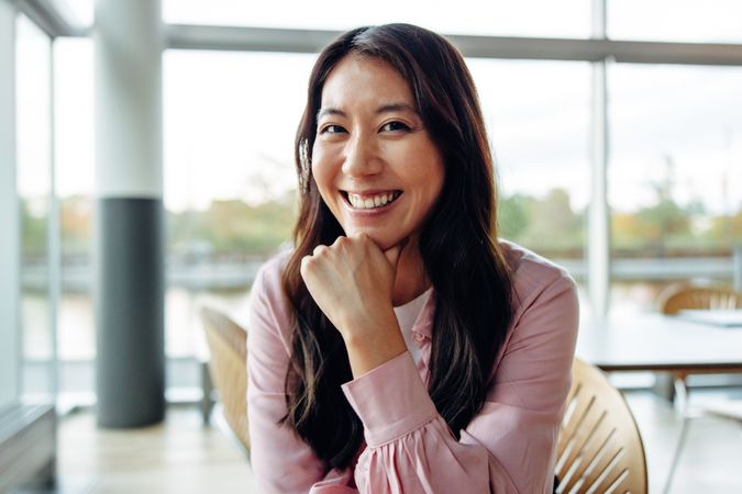 Beautiful Asian woman smiling at camera in large office space
