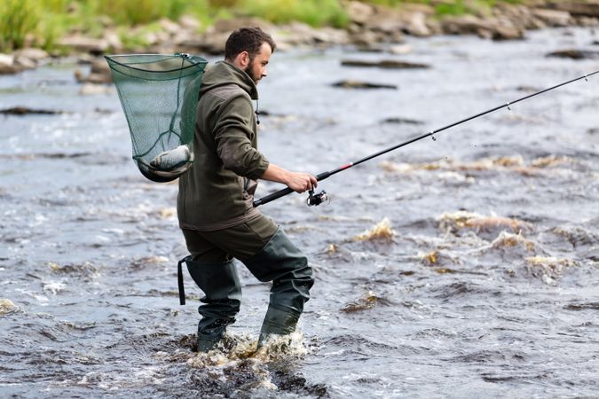 Fisherman crossing river with fish