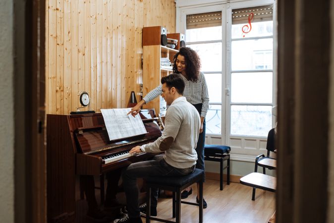 Man playing piano near woman teaching in studio