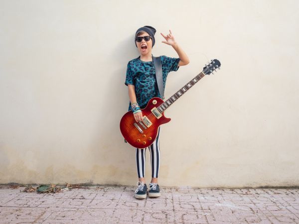 Energetic kid gesturing rock holding guitar
