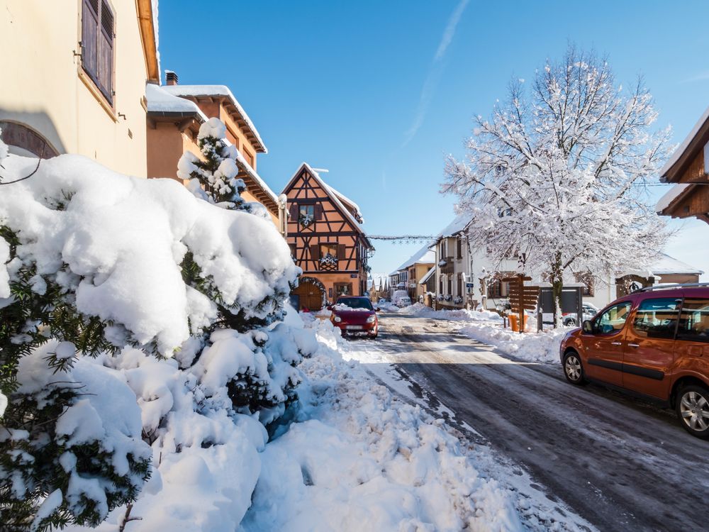 Sunny winter day. Snow-covered roofs of houses. Village in Alsace.