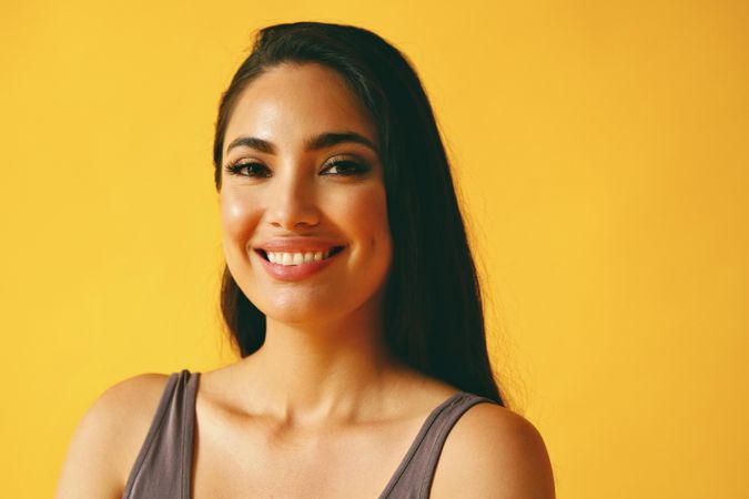 Smiling Hispanic woman looking confidently at camera in yellow room