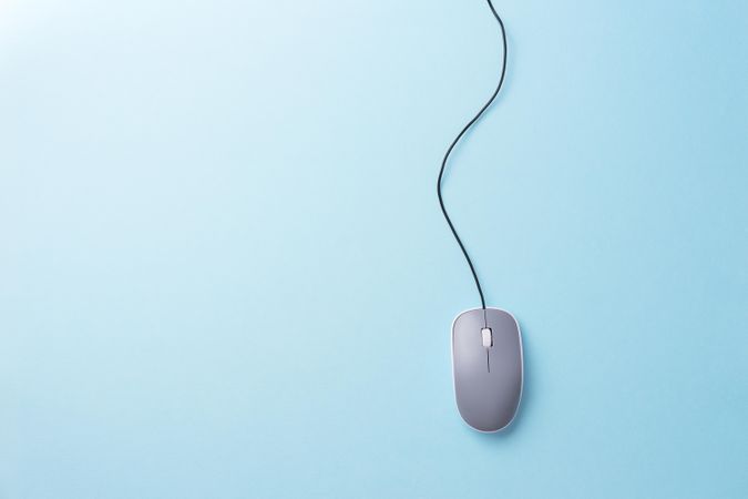 Computer mouse with cable attached on light blue background