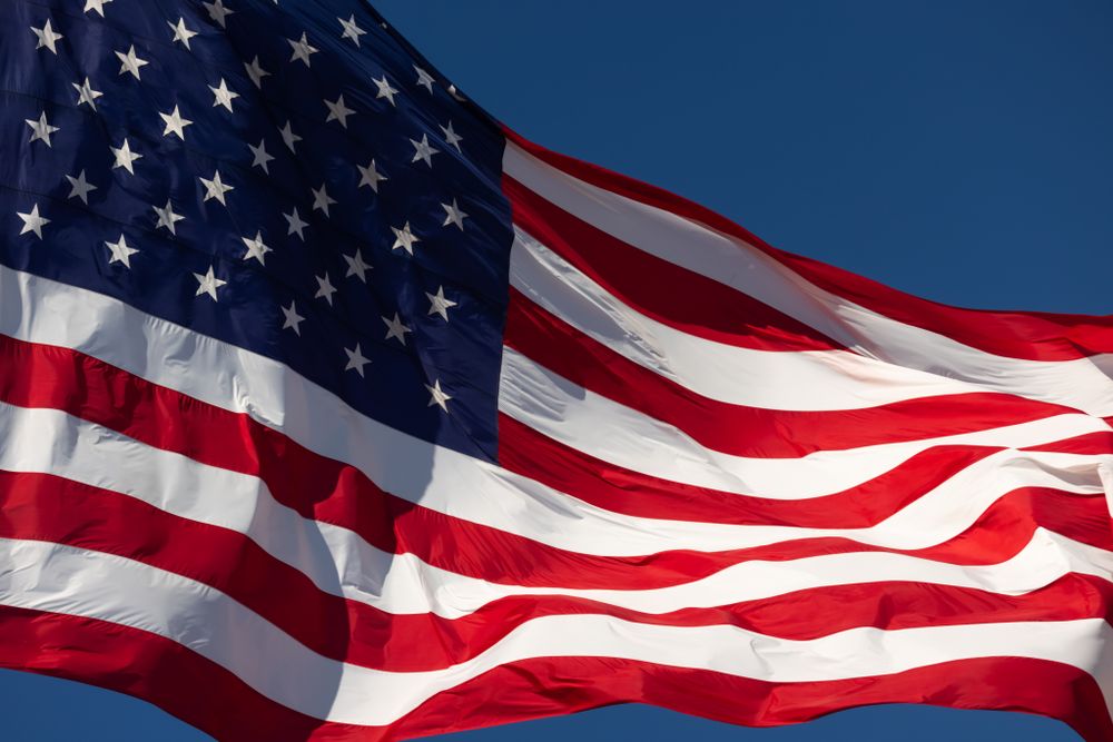 American Flag Waving In Wind Against a Deep Blue Sky.