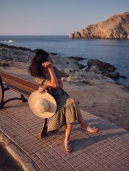Female admiring blue sea and sitting on wooden bench
