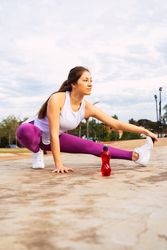 Young sportswoman stretching legs while exercising