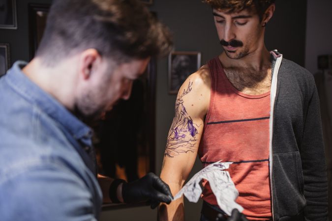 Tattoo master removing template on client's forearm