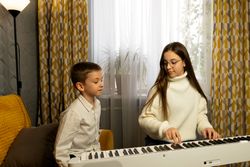 Young girl teaching boy to play the piano