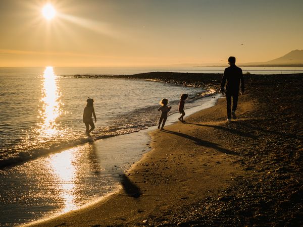 Anonymous father walking with children at sunset
