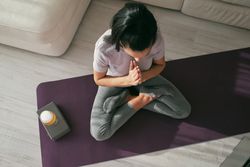 Woman meditating on mat with beer