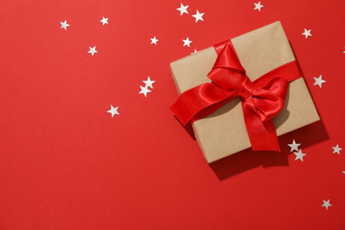 Gift box with bow on red background, space for text