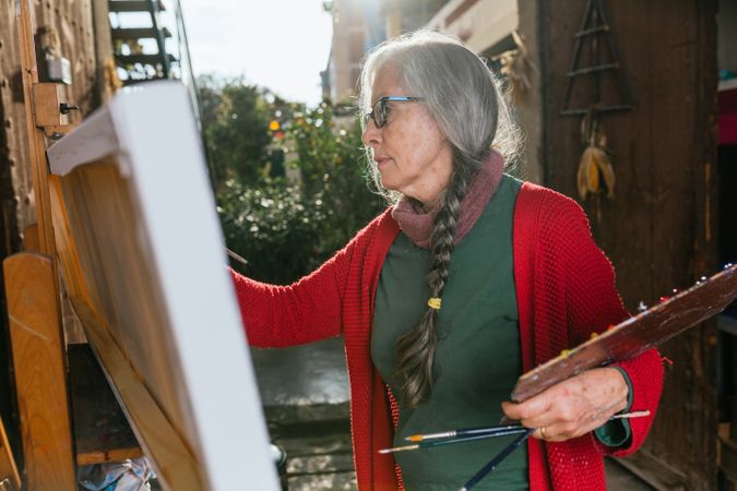 Mature woman painting on canvas in garden