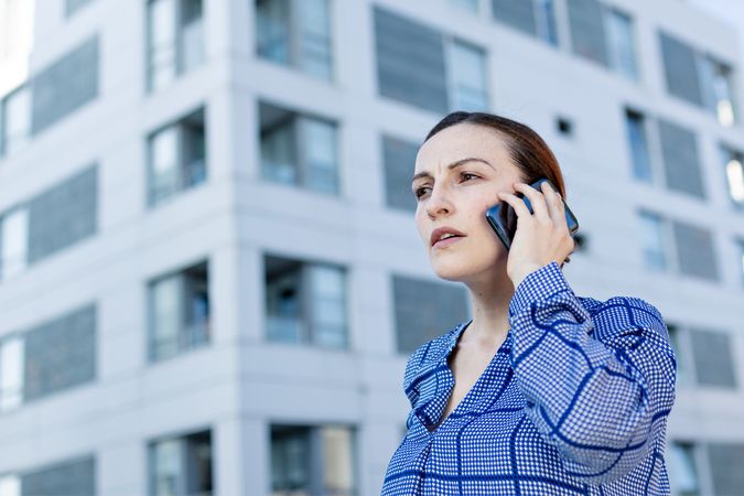 Serious manager speaking on phone on street