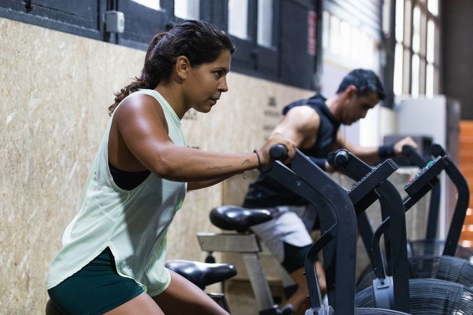 Determined Hispanic sportswoman exercising on air bike