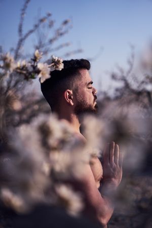 Shirtless man meditating in spring garden
