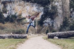 Excited man jumping on trunk in nature
