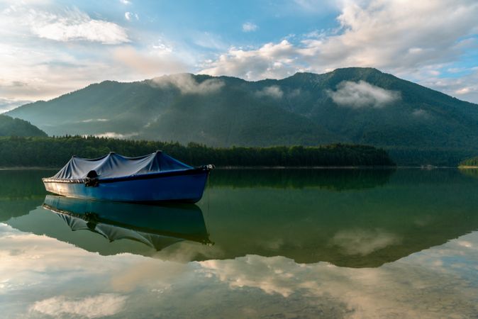 Landscape with a boat on Lake Sylvenstein and the mountains reflected in the water