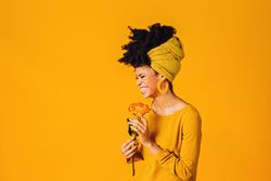 Portrait of smiling Black woman holding a rose to her nose
