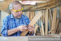 Asian male carpenter sizing wooden panel 5qkkXK