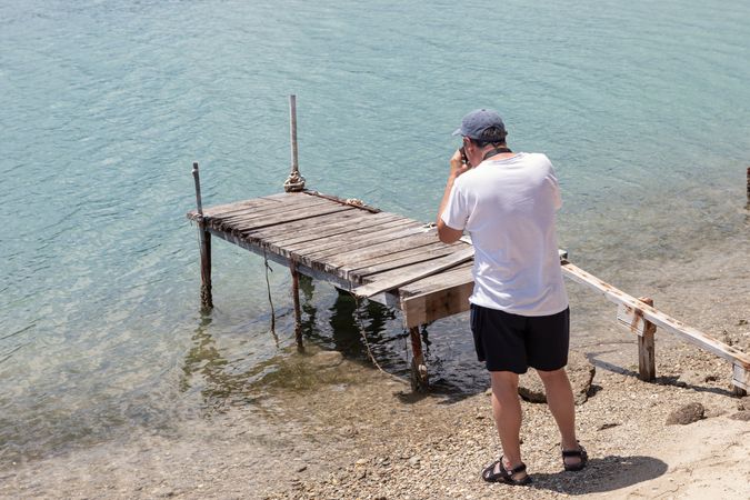 Man taking picture of broken old pier