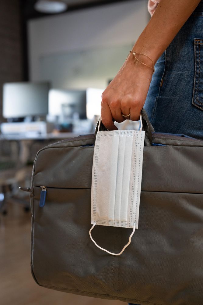 Person holding a computer case and facemask