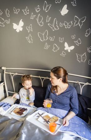 Mother and son having breakfast in bed