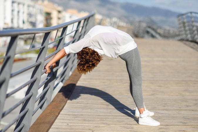 Woman doing bridge stretch on railing