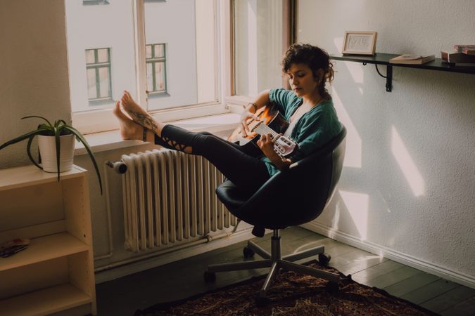 Content woman playing guitar at home