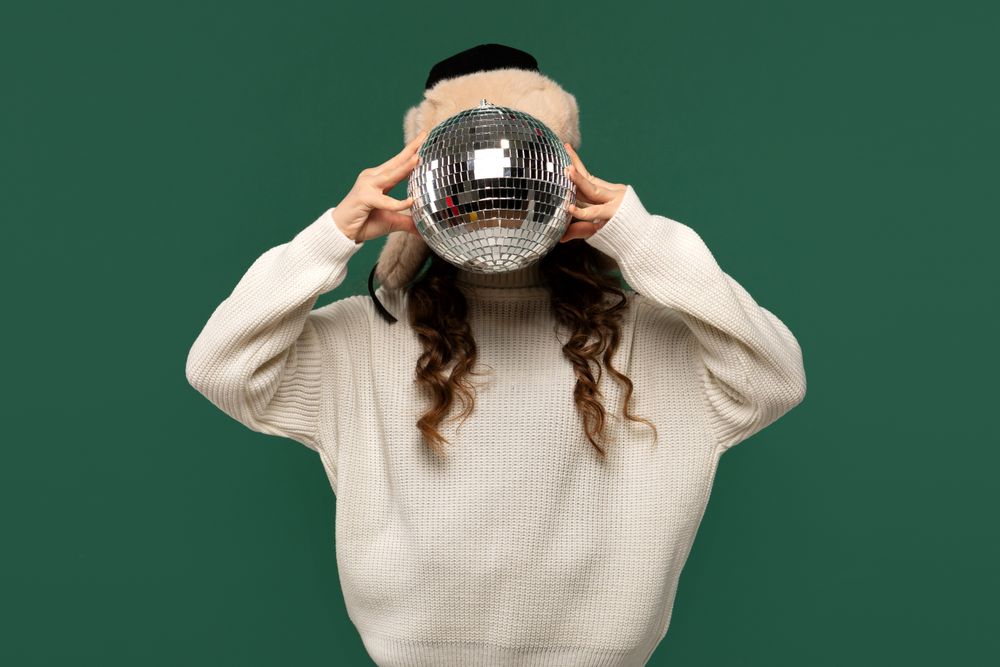 Girl playfully covering face with reflective disco ball