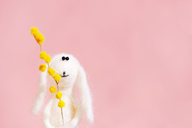 Adorable plush bunny holding yellow flower