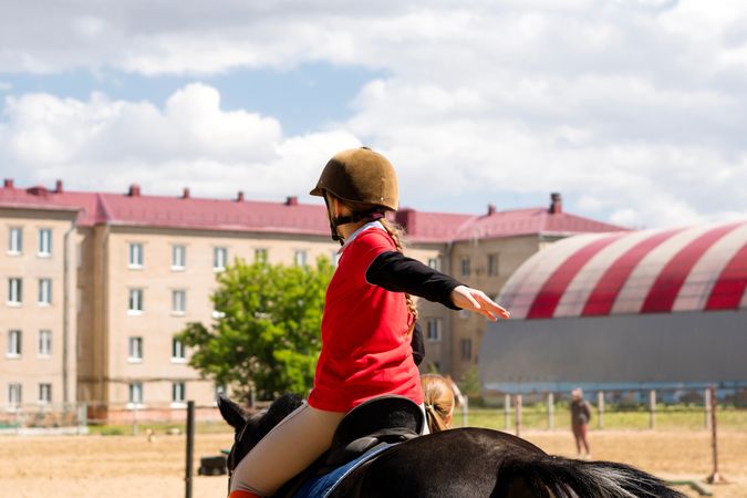 Young rider practices posture during outdoor equestrian training session.