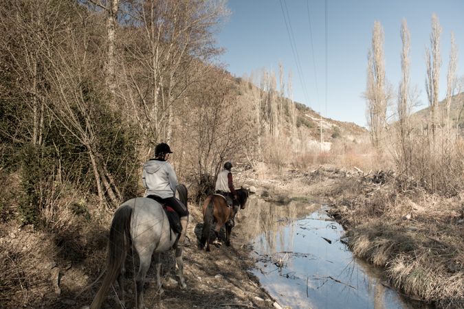 Anonymous people riding horses in brook