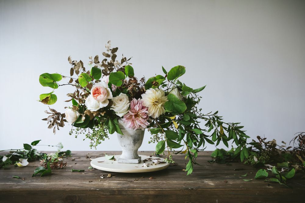 Composition of flowers and plants in vintage vase on board