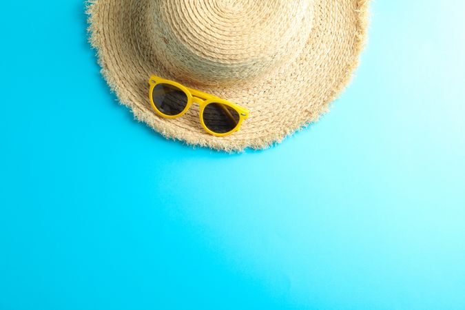 Straw hat and sunglasses on color background, space for text