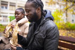 Companionship and Comfort: Friends Sharing a Meal on Park Bench in Fall