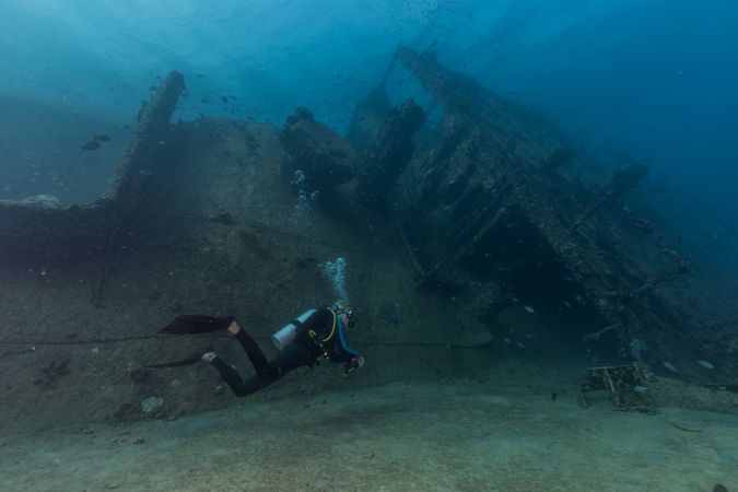 Scuba divers swimming underwater exploring wreckage