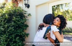 Black woman greeting and embracing female friend for having a new house 0WeGW4