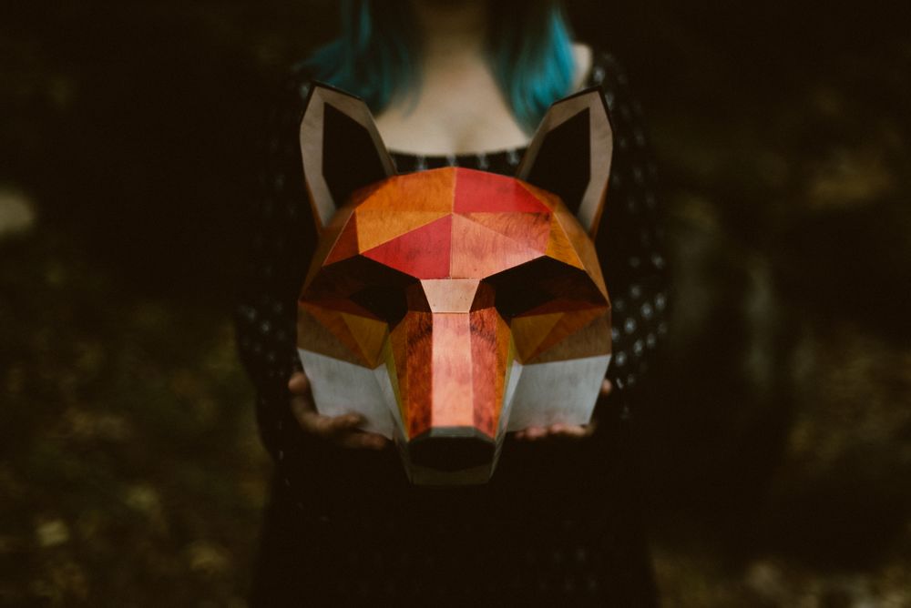 Woman showing red fox mask in forest