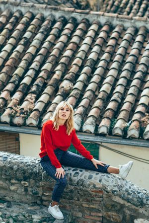 Female in red shirt sitting among rooftops outdoors