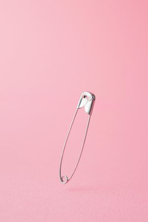 Close up of one safety pin on pink background