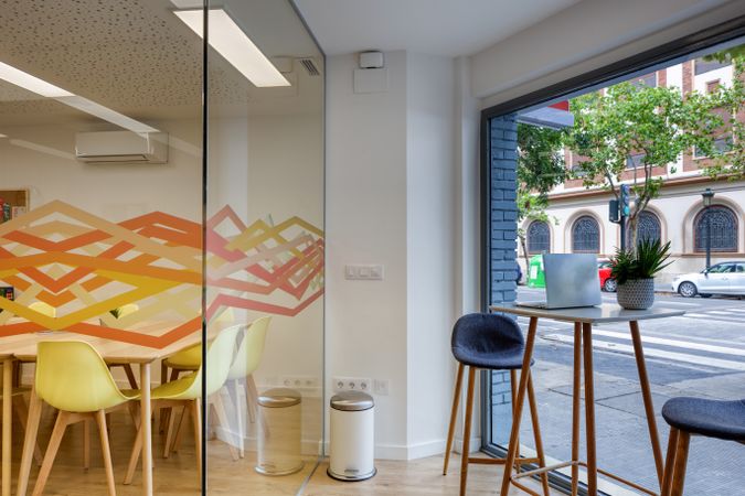 Interior of light modern office with colorful furniture against big window