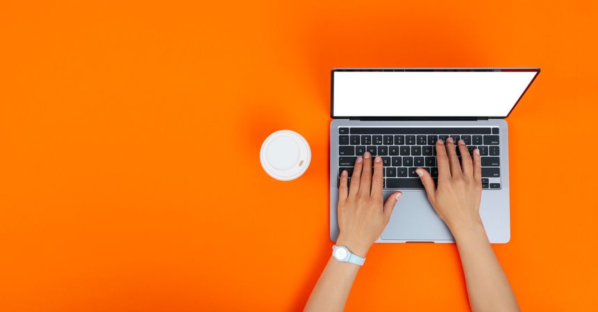 Banner of person using laptop on orange desk with take away cup of coffee or tea with copy space