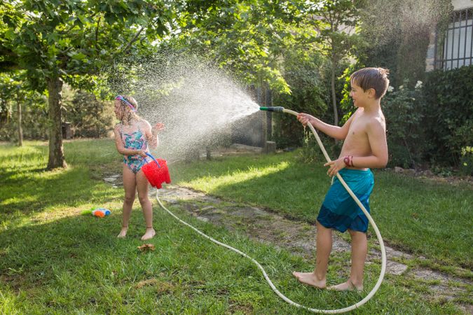 Little kids in swimwear having fun with splashing water