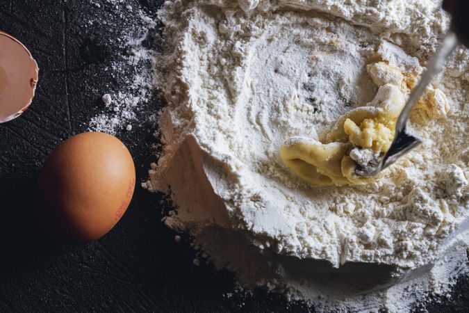 Broken egg and flour on dark background