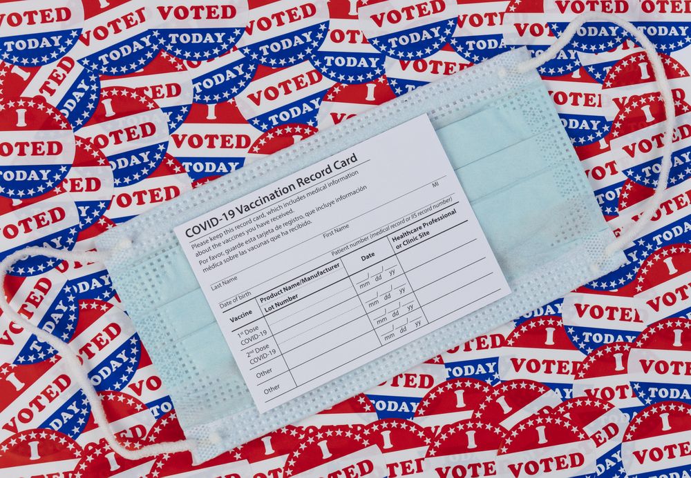 Covid 19 vaccine record card on top of I voted today stickers background with United States national colors
