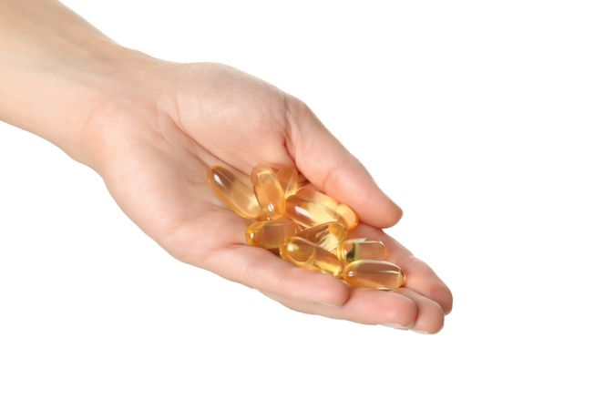 Omega pills in hand, isolated on blank background